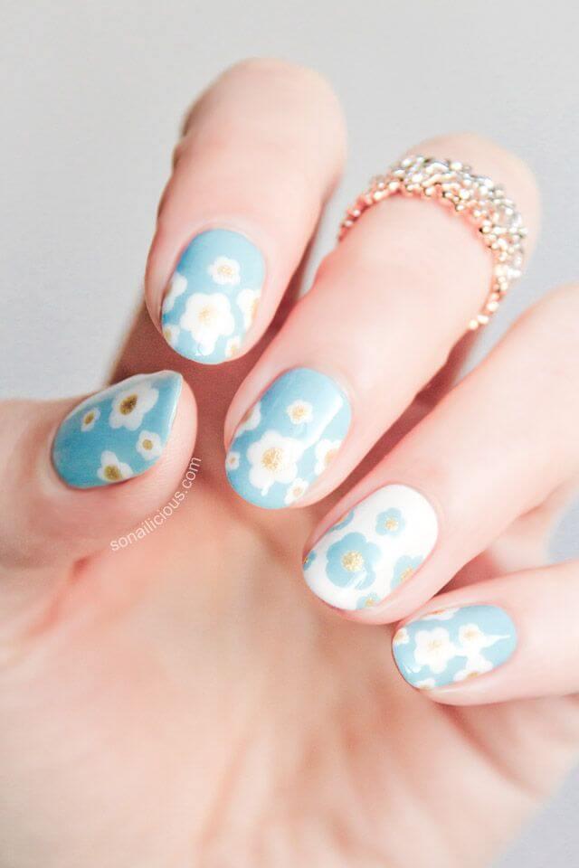 Ongles bleu clair avec des fleurs facilement dorées et blanches